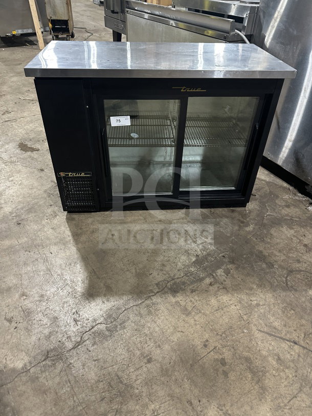 True commercial stainless steel refrigerated beer cabinet, model TBB-24-48G-SD-LD. Features view-through sliding doors, stainless worktop, and poly-coated wire rack. Serial number 87664332. 115V, 1 Phase.
