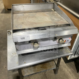 Stainless steel countertop gas griddle with dual control knobs. Used condition with signs of wear. Ideal for commercial use.