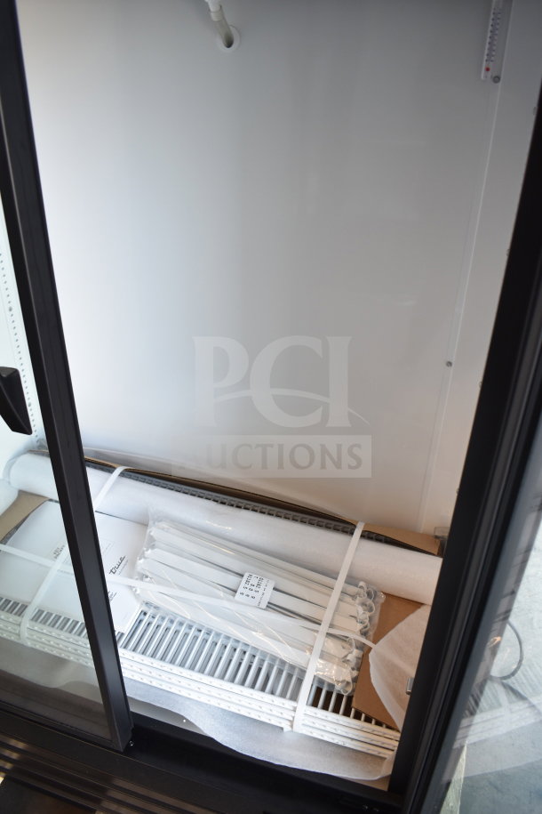 Brand new True TVM-36SL-HC commercial two-door reach-in cooler merchandiser, 115 volts, with parts visible inside.