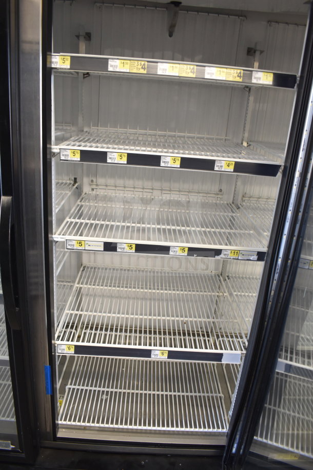2018 True GDM-72F-HC commercial three-door reach-in freezer merchandiser. Features empty wire shelves and visible pricing labels.
