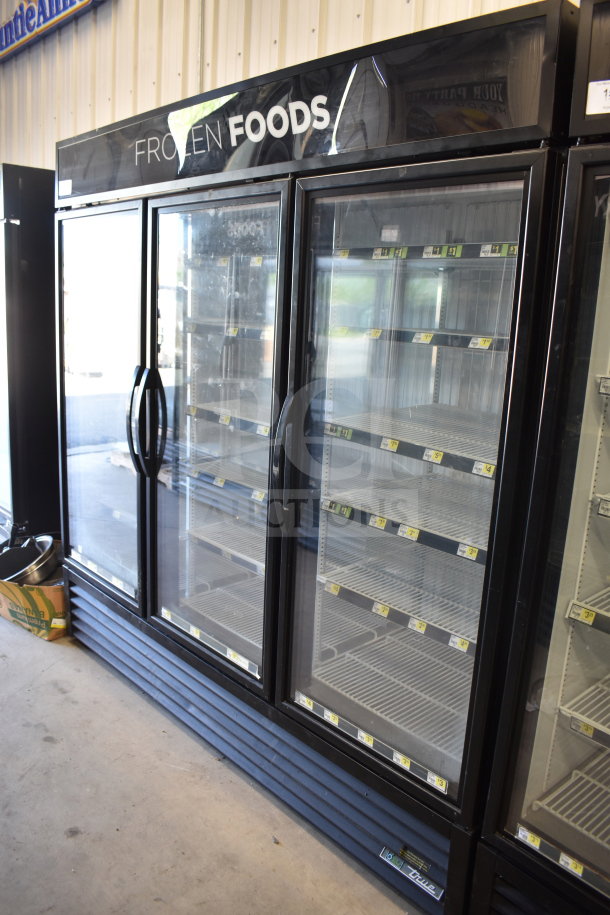2018 True GDM-72F-HC commercial 3-door freezer merchandiser, 115 volts, black frame, good condition, shelves labeled for organization.