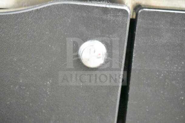 Close-up of a black surface with a shiny metal lock on the Ozark River Portable Sink. This image shows part of the sink's exterior detail.