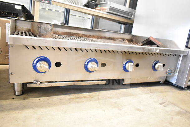 Globe Commercial countertop gas charbroiler grill with four blue control knobs. Stainless steel, moderate wear visible.