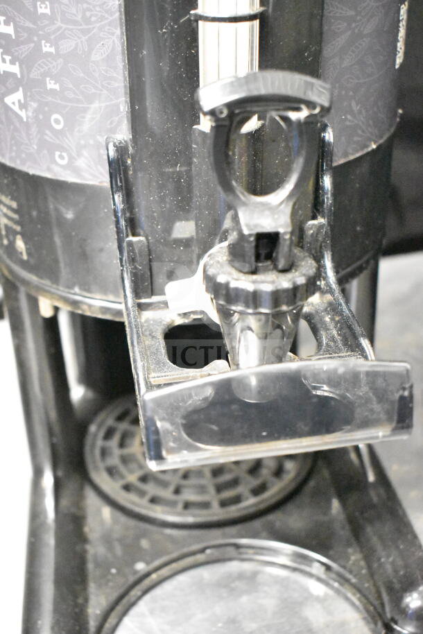 Two black countertop beverage holder dispensers, with sturdy spigot and drip tray. Light wear visible. Ideal for cafes.