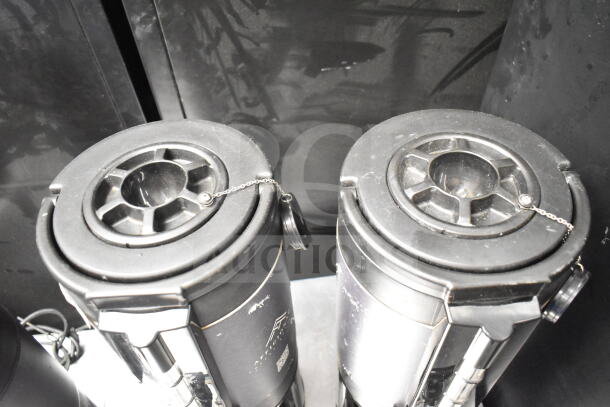 Two countertop beverage holder dispensers with black lids and chrome accents. Slight wear visible.