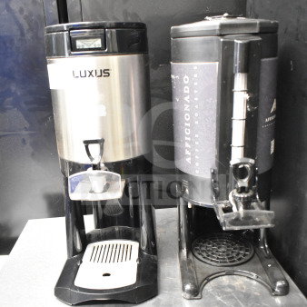 Pair of Luxus countertop coffee dispensers, stainless steel and black plastic, with drip trays. Visible branding includes "Luxus" and "Aficionado Coffee Roasters." Condition appears used.