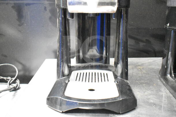 2 Luxus countertop coffee holder dispensers in black, used condition, with drip trays and visible dispensers, ideal for coffee stations.