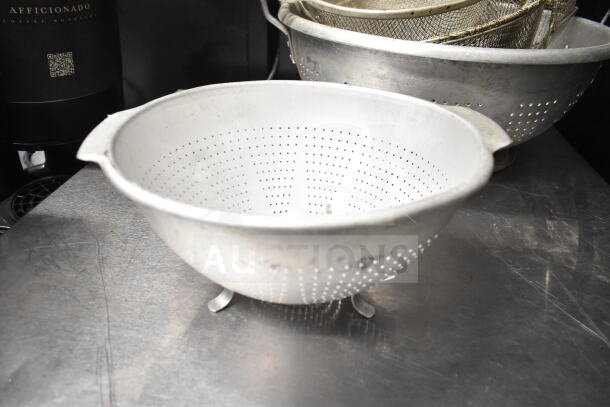 Metal colander and strainer set; includes various pieces, vintage condition, ideal for kitchen use or decor.
