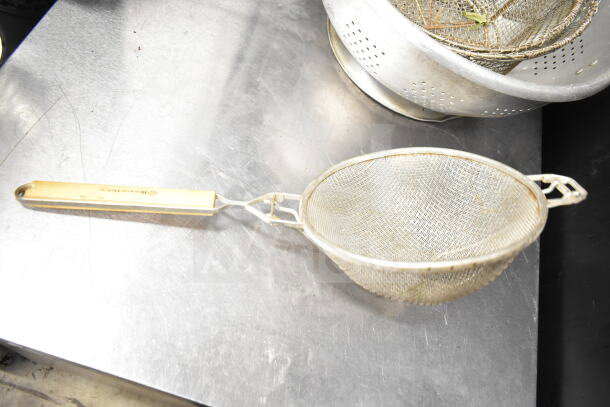 Mesh strainer with wooden handle, part of an 8-item auction lot including colanders. Pre-owned, visible wear.