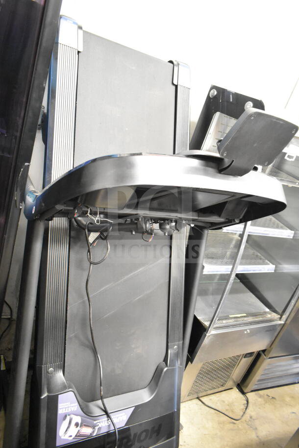 Horizon Folding Treadmill, compact design, black finish, foldable for easy storage, cords visible, ideal for home gyms.
