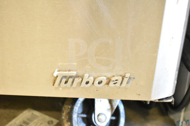 Turbo Air MST-28-12 logo on commercial refrigerated prep table; visible wheel; stainless steel finish.
