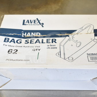 Brand new Lavex 562BAGSEALER bag sealing tape dispenser in box with scratch and dent. Box shows tape, markings, and damage.