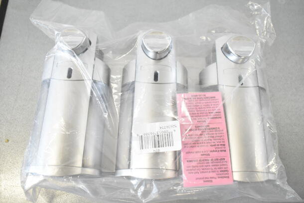 3-Chamber wall-mounted soap dispenser, satin silver, with translucent bottles, packaged in plastic. Barcoded tag visible.