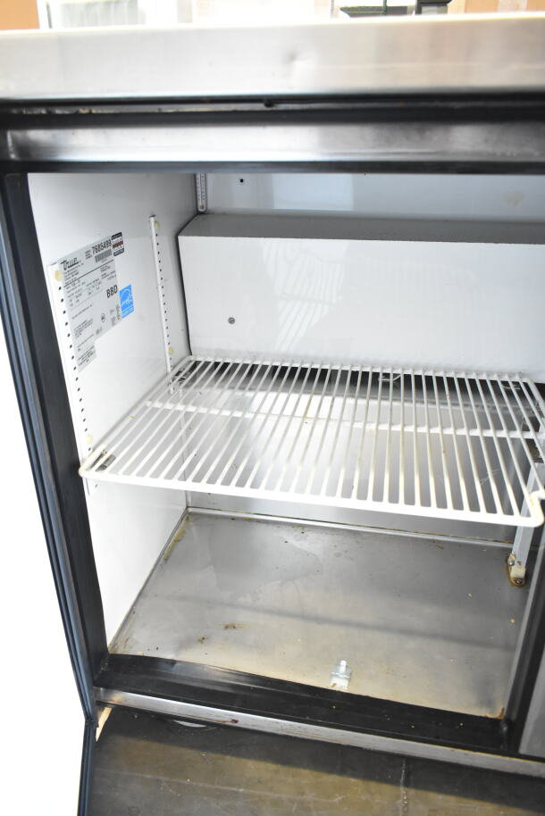 True TUC-72 commercial cooler, 3-door undercounter model on casters, visible interior shelf, label shows 115 volts, 1 phase.