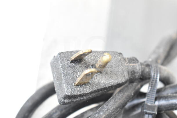 Close-up of a black power plug for the 2021 True STG1F-2HSLH-HC commercial freezer, showing three prongs.