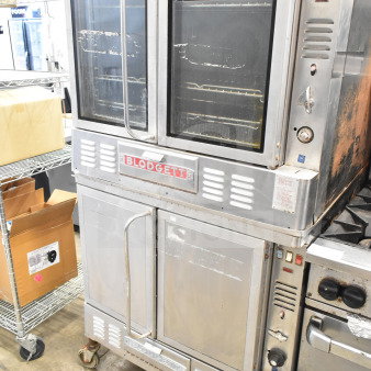 Blodgett commercial gas convection oven, dual units on casters, stainless steel, visible wear, Blodgett logo on front.