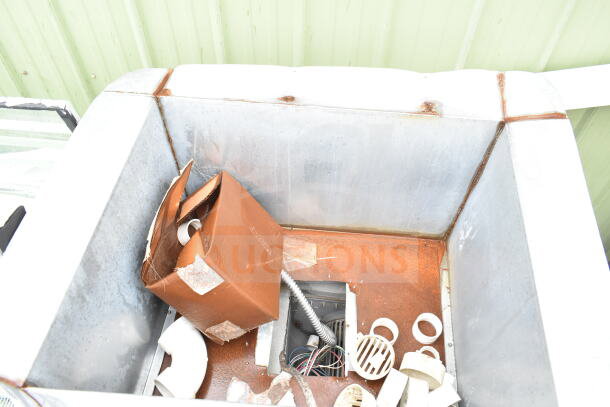 Commercial floor unit interior with visible rust, containing assorted pipes and a cardboard box. Used condition.