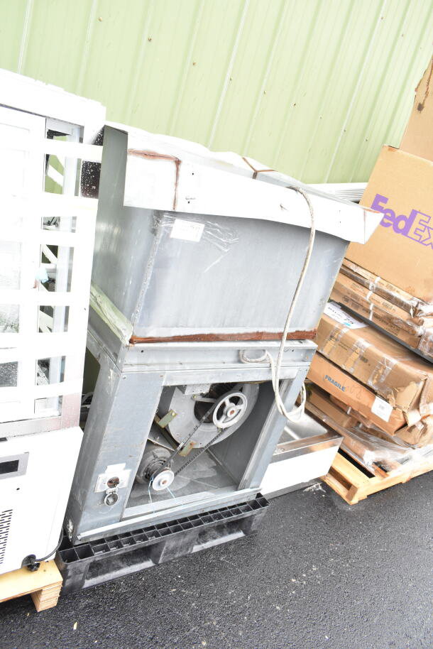 Industrial commercial floor-style unit with visible pulley system and metal casing. Moderate wear, in outdoor setting.