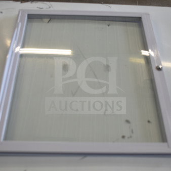 Brand new scratch and dent sliding door for freezer merchandiser, glass panel with white frame, visible wear.