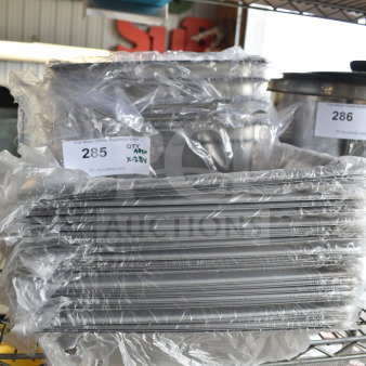 Stack of new stainless steel steam table pans in plastic, with auction label "285" indicating 28 items total.