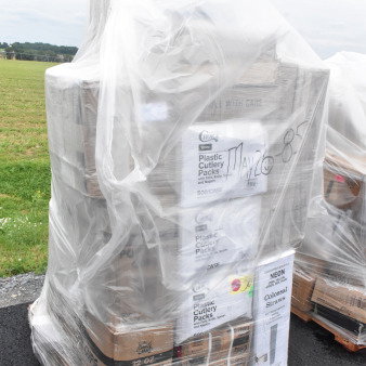 Pallet of brand new scratch and dent items including straws, pizza boxes, portion cups, and cold cups, wrapped in plastic.