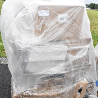 Pallet of 25 new scratch and dent items including glasses, bowls, tongs, and shelf brackets wrapped in plastic. Auction lot MAY26-64.