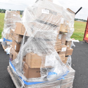 Large pallet wrapped in clear plastic containing multiple cardboard boxes labeled with various product types, such as wine glasses and dishers; items are described as brand new with scratch and dent condition.