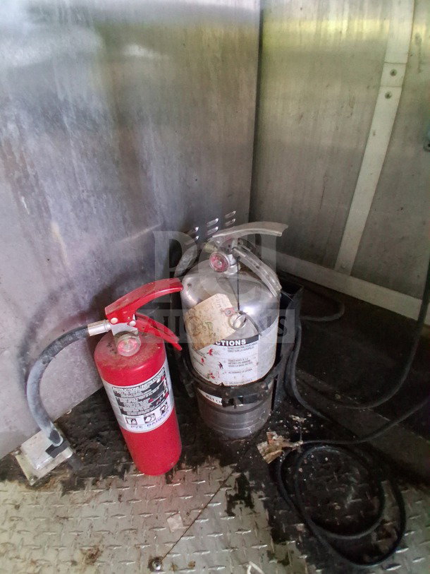 Alt Text: Interior of 2020 Diamond Cargo Mobile Kitchen showing fire extinguishers on metal floor.