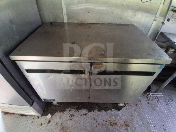 Stainless steel Arctic Air refrigerator inside 2020 Diamond Cargo 24' Custom Mobile Kitchen, showing wear but functional.