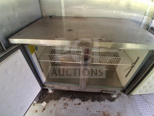 Open stainless steel refrigerator inside 2020 Diamond Cargo 24' Mobile Kitchen, featuring wire shelving and visible interior wear.