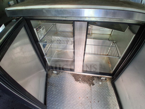 Interior view of Arctic Air commercial fridge from a 2020 Diamond Cargo 24' Custom Mobile Kitchen. Features stainless steel shelves and visible wear.