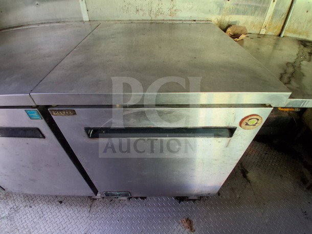 Stainless steel commercial freezer in 2020 Diamond Cargo mobile kitchen. Features visible tags and stainless steel surface.
