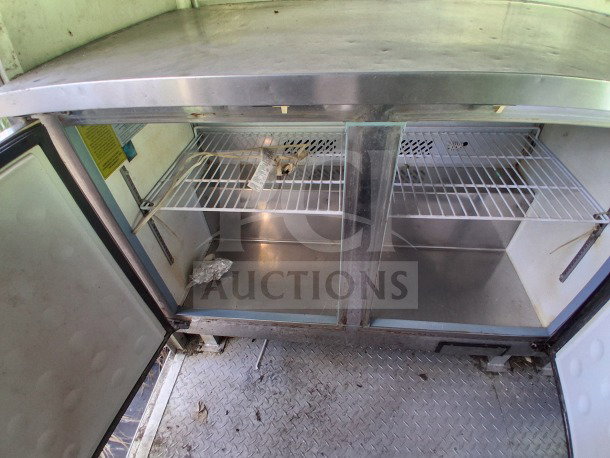 Stainless steel interior of 2020 Diamond Cargo mobile kitchen, showing double-door refrigeration with wire shelving.