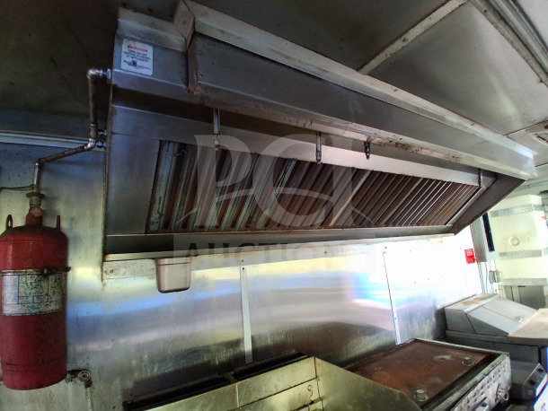 Interior of 2020 Diamond Cargo 24' Mobile Kitchen with stainless steel finish, large commercial griddle, and Pyro-Chem fire system.