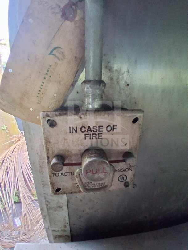 Pyro-Chem fire suppression pull station in mobile kitchen, marked "IN CASE OF FIRE." Slight wear visible, for safety use.