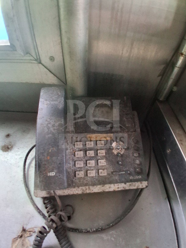 Dusty telephone on a stainless steel surface inside a mobile kitchen. Keypad and buttons visible.