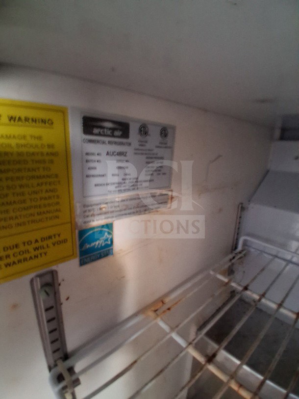 Arctic Air refrigeration interior with visible labels including model: AUC48RZ. Features warning and energy star stickers.