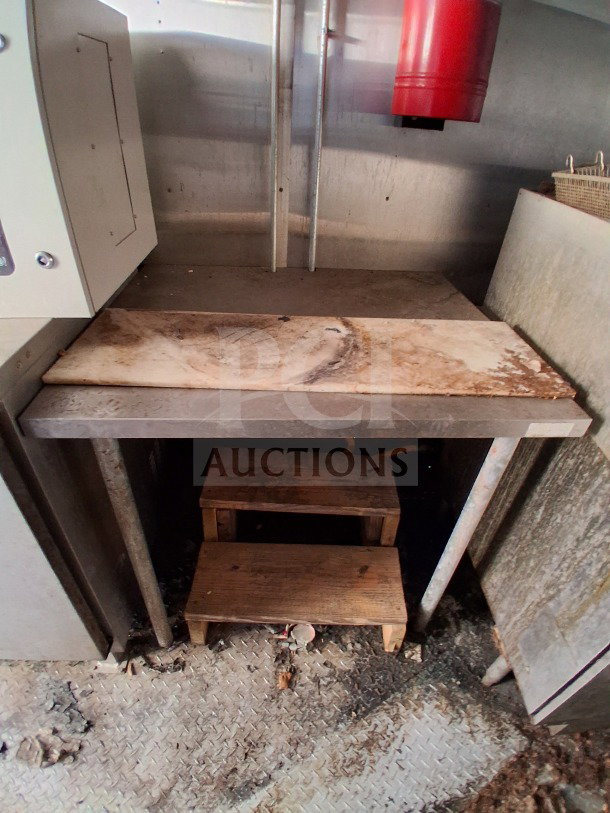 Interior of a 2020 Diamond Cargo 24' Custom Mobile Kitchen with stainless steel surfaces and wooden platform in used condition.