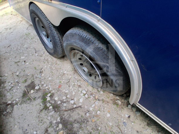 24ft D&A Custom Mobile Kitchen, dark blue wrap, dual wheels, visible wear on tire tread, suitable for high-volume service.