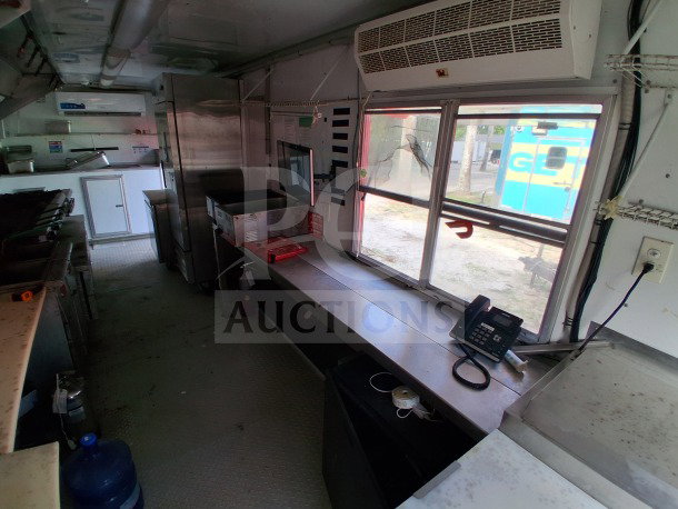 24FT D&A Custom mobile kitchen with dark blue wrap. Features double Avantco deep fryers, refrigeration suite, and air curtain units.