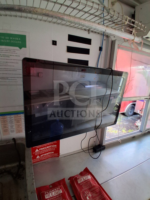 2019 D&A Custom mobile kitchen interior, showing prep tables, refrigeration unit, fire extinguisher, and safety blankets.