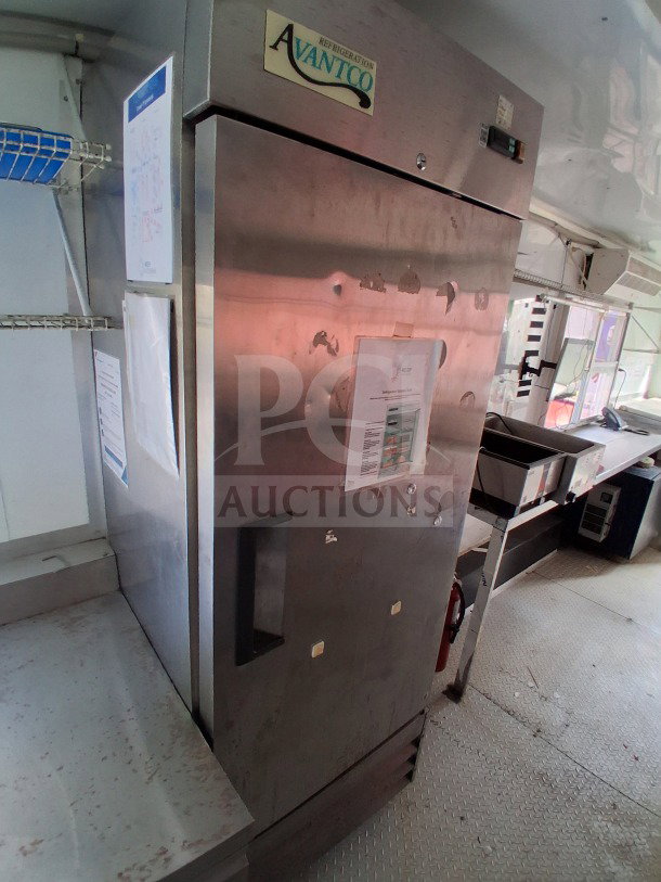 Avantco refrigerator inside a 2019 D&A Custom 24ft mobile kitchen, featuring stainless steel finish and attached documents.