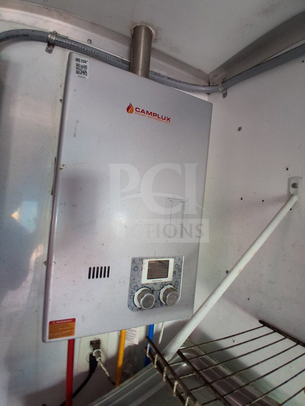 Camplux water heater unit inside a 2019 D&A custom mobile kitchen trailer. Visible pipes and wiring connected.