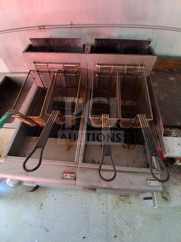 Dual Avantco deep fryers in stainless steel, part of a 24FT 2019 D&A Custom mobile kitchen, showing baskets and surface wear.