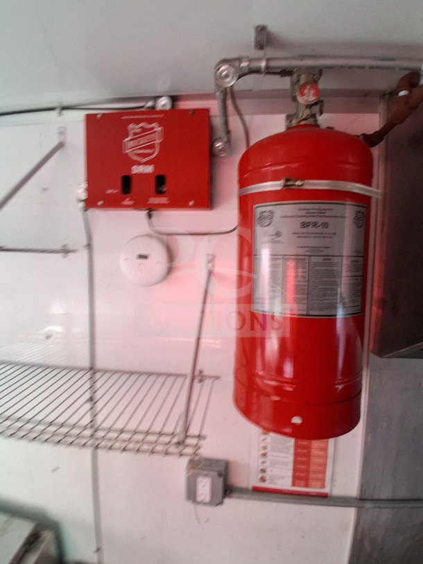 Fire suppression system inside 2019 D&A Custom Mobile Kitchen. Red tank and control box on wall. Safety feature for kitchen use.