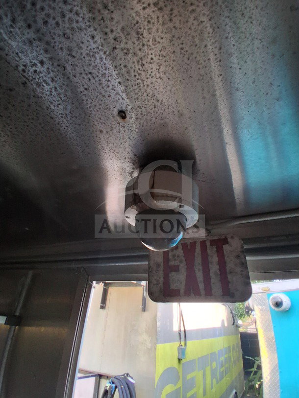 Interior of a 2019 Diamond Cargo mobile kitchen showing a ventilation dome camera and a weathered exit sign.
