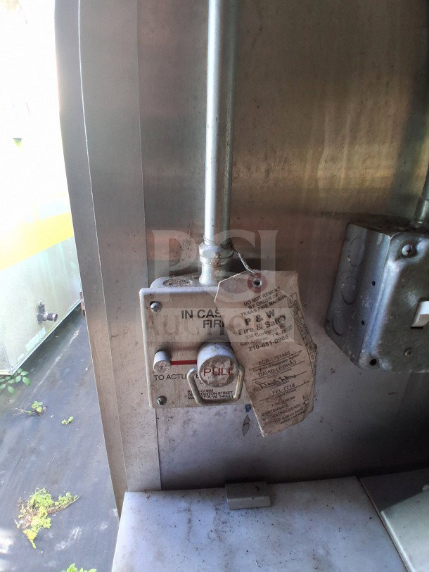 Fire safety pull station inside the 2019 Diamond Cargo mobile kitchen, with attached inspection tag.