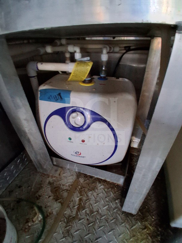 Close-up of a corner inside the 2019 Diamond Cargo 24' mobile kitchen. Image shows a dirty electrical or plumbing component beneath a metal shelf, needing cleaning.