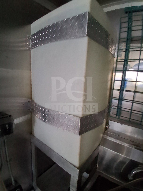 2019 Diamond Cargo 24' mobile kitchen interior, showcasing plumbing tank with metal straps, in need of deep cleaning.