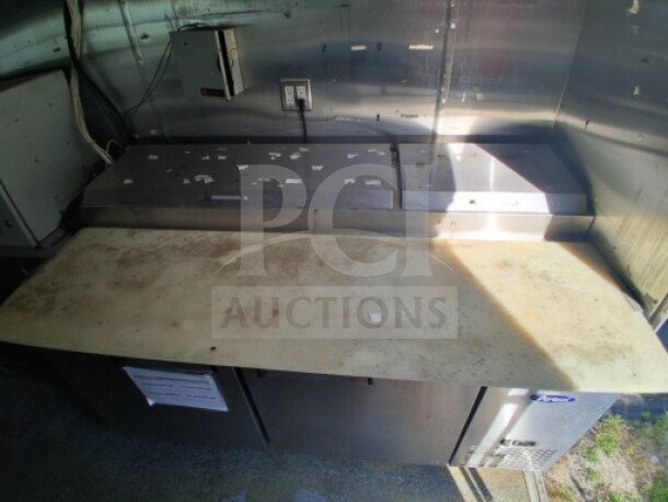 2019 Quality Cargo food trailer interior with stainless steel countertops, grease hood, refrigeration units, and cooktop.